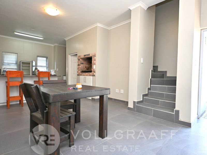 Open plan living area featuring a built-in braai, tiled flooring, and a staircase leading to the upper level.