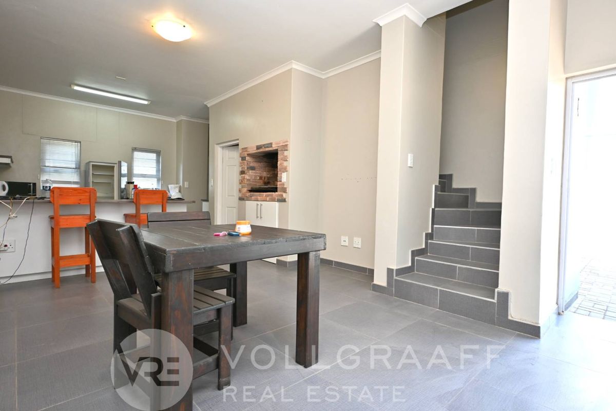 Open plan living area featuring a built-in braai, tiled flooring, and a staircase leading to the upper level.