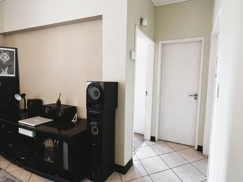 A living area featuring tiled flooring, neutral wall finishes, and access to adjacent rooms via a standard internal door.