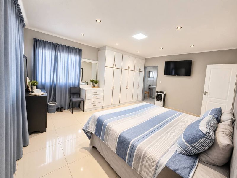 Spacious bedroom featuring neutral tiled flooring, extensive built-in cabinetry, recessed downlighting, and direct access to an en-suite bathroom.