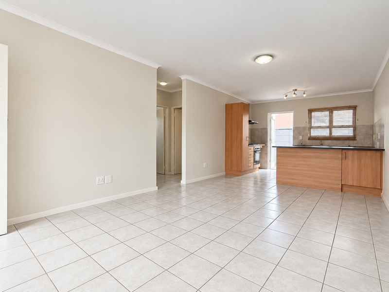 Spacious open-plan living area featuring tiled flooring and a functional kitchen with built-in cabinetry, island, and integrated appliances.