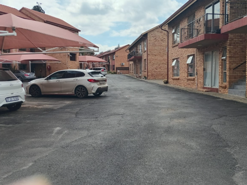 Exterior view of a townhouse complex featuring brick facades, asphalt driveway, and covered parking bays.