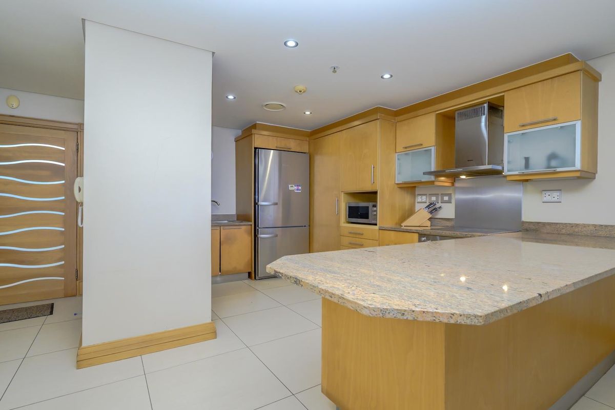A functional kitchen featuring light wood cabinetry, granite countertops, a breakfast bar, and integrated stainless steel appliances with modern recessed lighting.