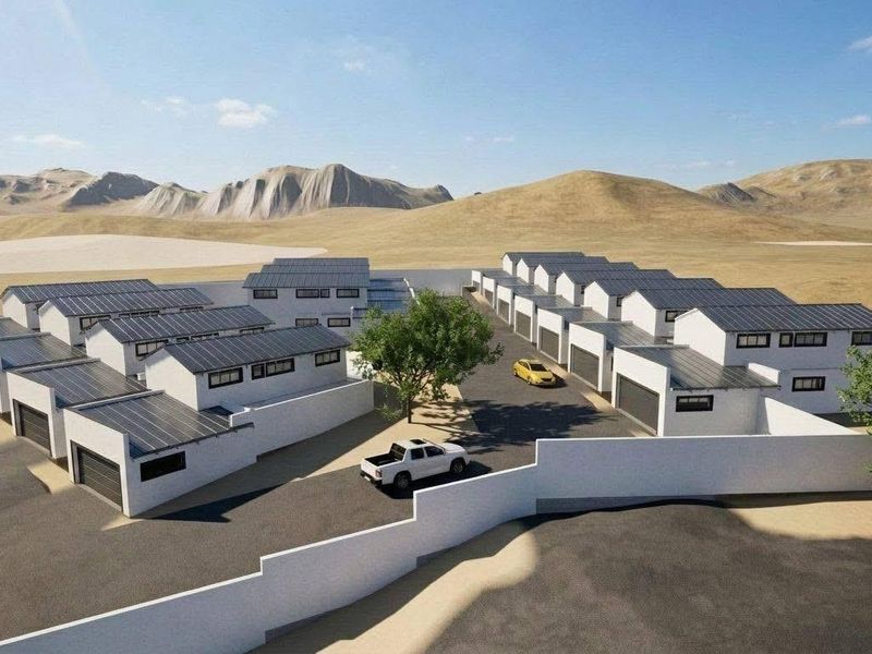 Aerial view of a modern townhouse complex featuring multiple units with solar panels, paved driveways, and secure boundary walls.