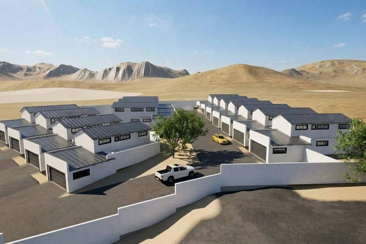 Aerial view of a modern townhouse complex featuring multiple units with solar panels, paved driveways, and secure boundary walls.