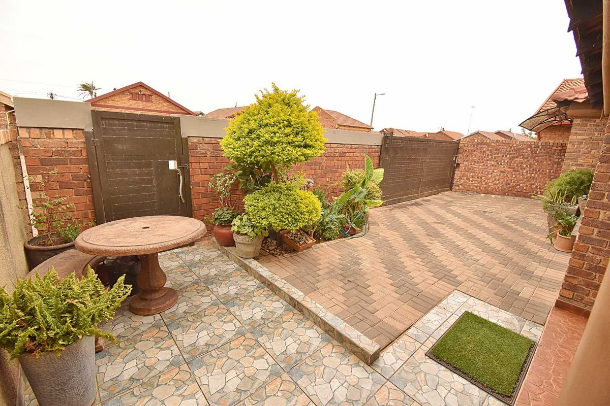 A private rear courtyard featuring a combination of paved and tiled surfaces, enclosed by brick boundary walls and a secure gate.