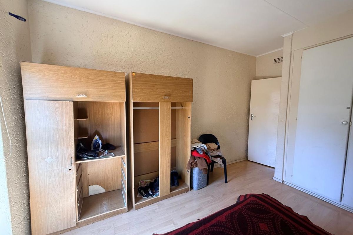A bedroom featuring laminate flooring and built-in cupboards, requiring cosmetic updates to improve the overall aesthetic and finish.