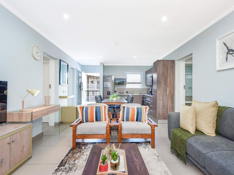 An open-plan living and kitchen area featuring modern tiled flooring, recessed lighting, and contemporary cabinetry, creating a bright and functional living space.
