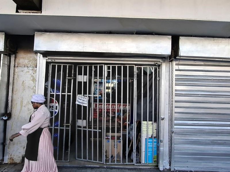 Street-level commercial shopfront featuring metal security gates and roller shutter doors, showing signs of wear and tear.