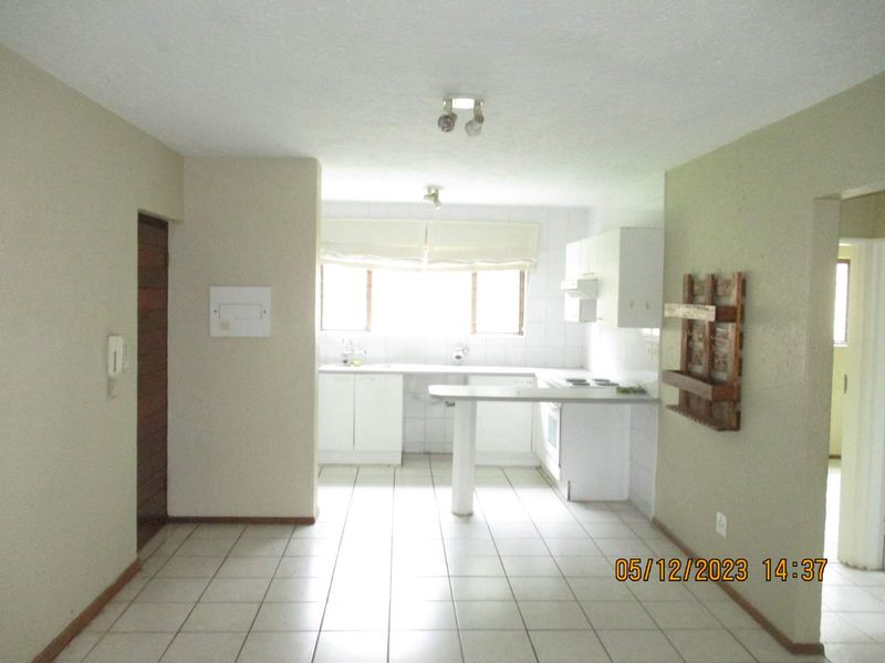 Open plan kitchen and living area featuring tiled flooring, built-in cabinetry, and a breakfast counter, offering a functional layout ready for modernization.