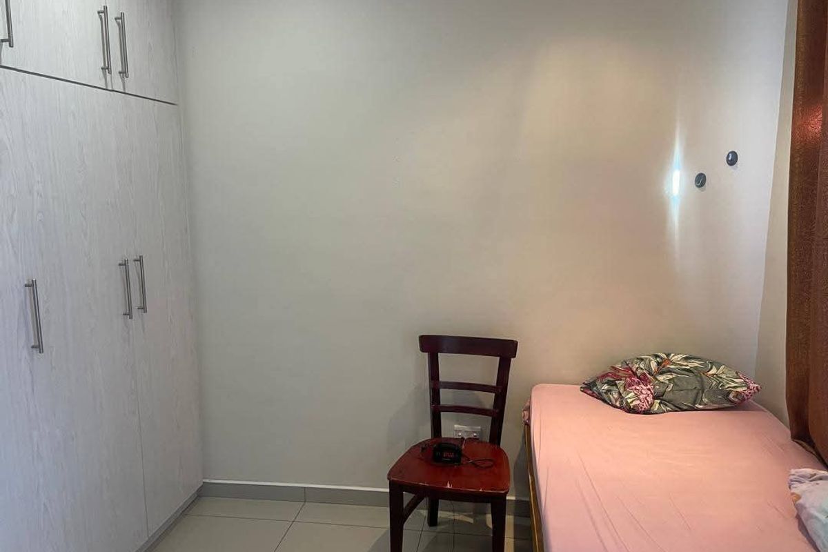 A compact bedroom featuring built-in floor-to-ceiling cabinetry with light wood-grain finish and tiled flooring.