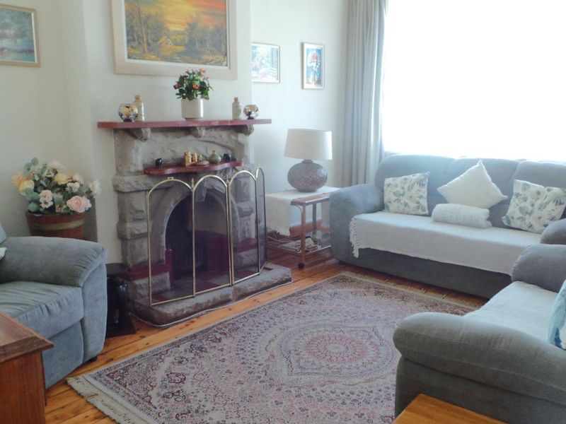 A cozy living room featuring a traditional stone fireplace and warm timber flooring, offering a comfortable and inviting atmosphere.