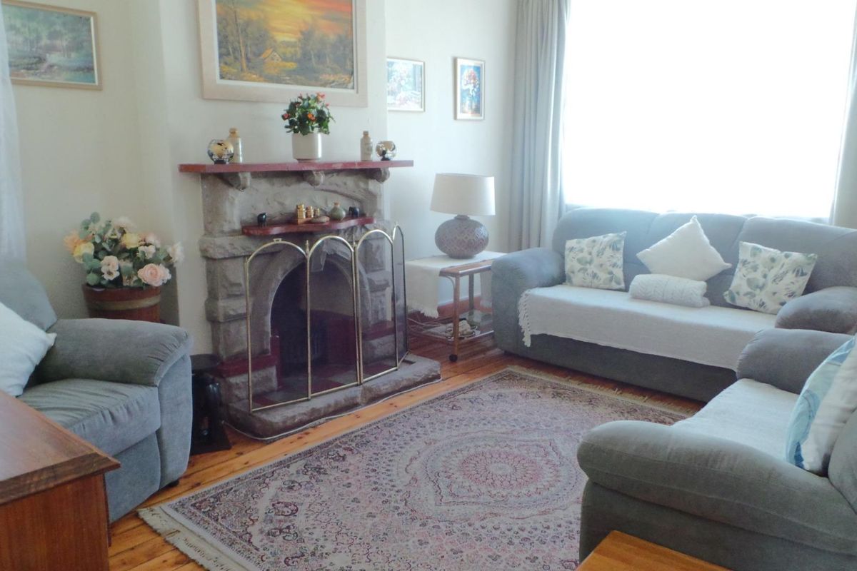 A cozy living room featuring a traditional stone fireplace and warm timber flooring, offering a comfortable and inviting atmosphere.