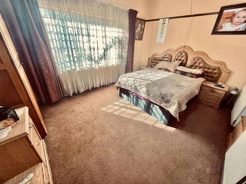 A spacious bedroom featuring carpeted flooring, a picture rail, and large windows with curtain rails, offering a blank canvas for modernization.