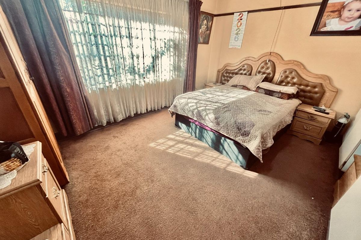 A spacious bedroom featuring carpeted flooring, a picture rail, and large windows with curtain rails, offering a blank canvas for modernization.