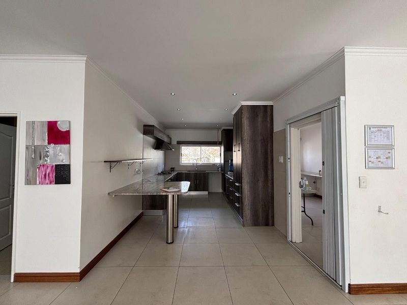 A modern, spacious kitchen featuring dark wood cabinetry, stone countertops, a breakfast bar, and tiled flooring, offering a clean and functional layout.