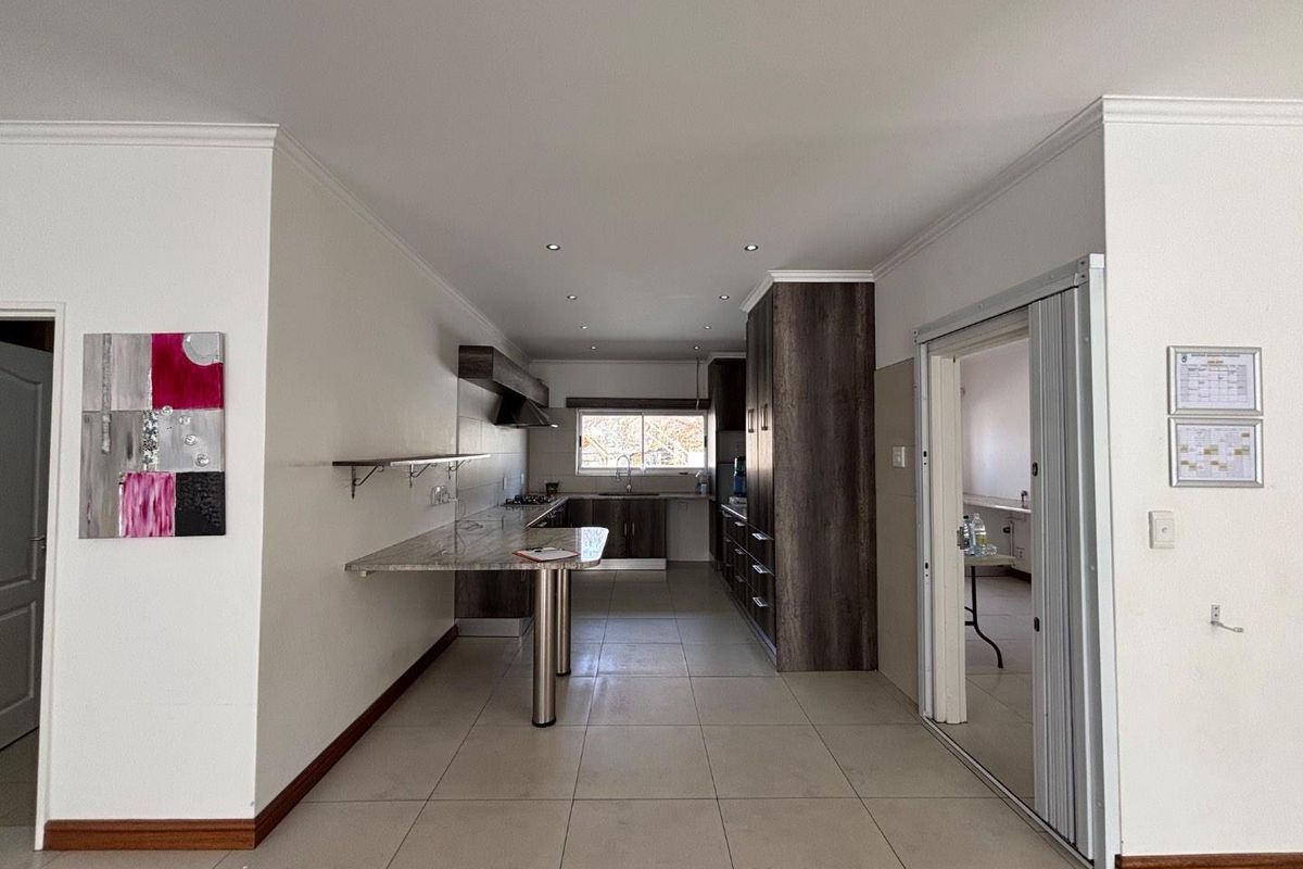 A modern, spacious kitchen featuring dark wood cabinetry, stone countertops, a breakfast bar, and tiled flooring, offering a clean and functional layout.