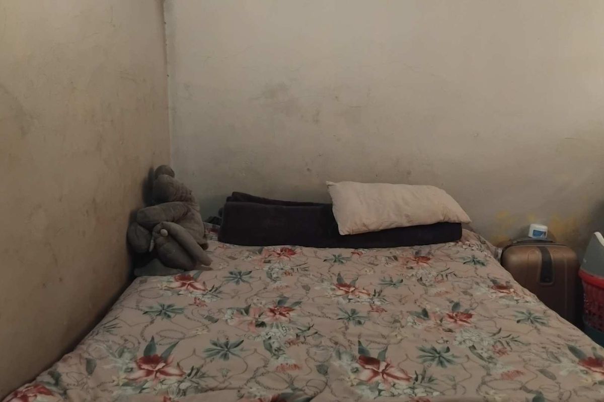A bedroom featuring plain walls with visible signs of wear and staining, requiring cosmetic attention.
