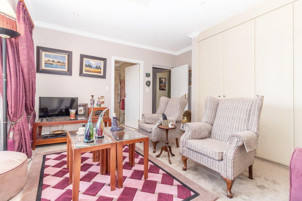 A comfortable bedroom featuring built-in cupboards, neutral carpeting, and direct access to an en-suite bathroom.