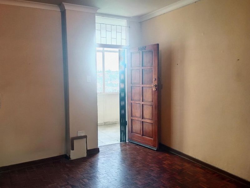 An empty entrance area featuring original parquet flooring, a solid wooden door, and access to an external balcony space.