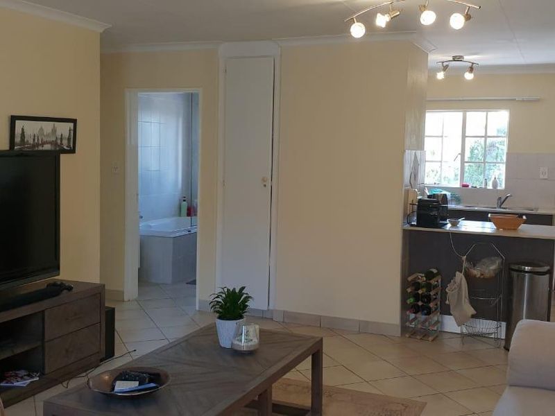 Open-plan living area featuring tiled flooring, integrated kitchen space with cabinetry, and direct access to a bathroom.