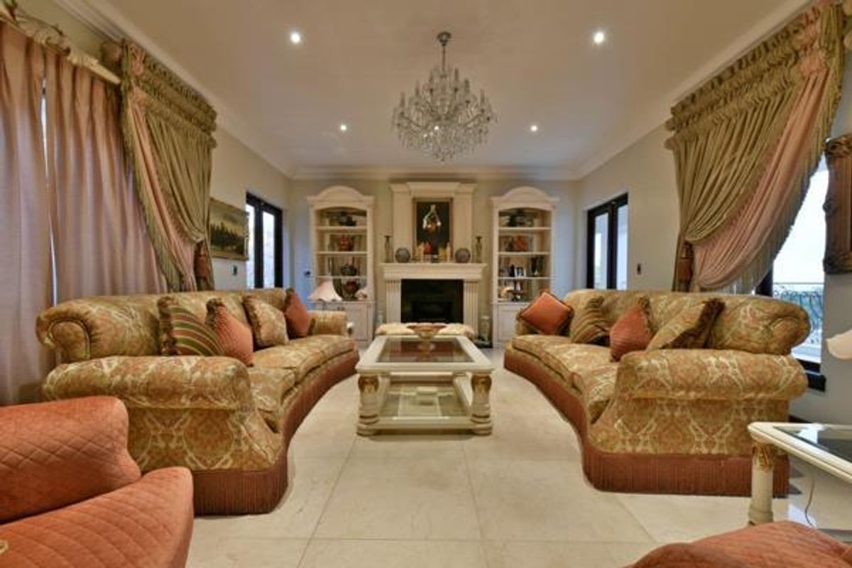 Elegant living room featuring a central fireplace with built-in shelving units, recessed lighting, and large windows with decorative drapery.