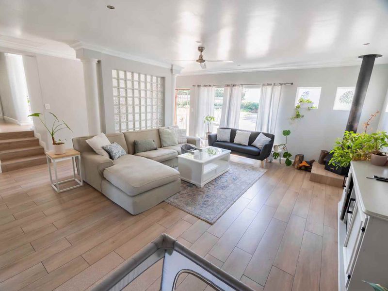 Spacious living room featuring light laminate flooring, a feature glass block wall, and a built-in wood-burning fireplace, creating a bright and inviting atmosphere.
