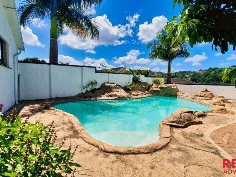 Outdoor pool area featuring a rock-scaped swimming pool, paved surround, and perimeter boundary wall.