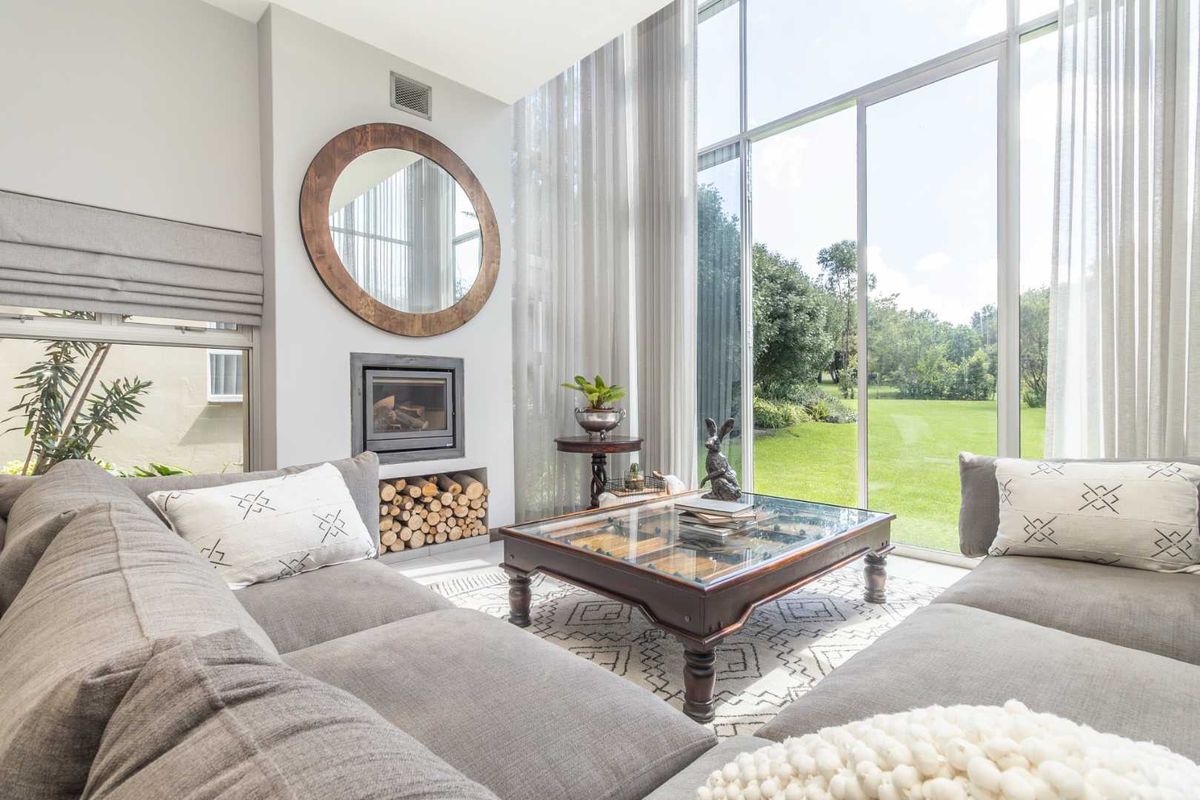 Bright living room featuring a built-in fireplace with log storage, floor-to-ceiling windows, and direct views of the garden.