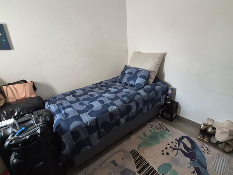 A compact bedroom featuring neutral wall finishes and laminate flooring, suitable for a single bed setup.