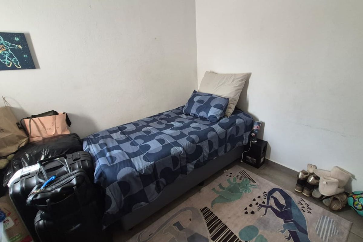 A compact bedroom featuring neutral wall finishes and laminate flooring, suitable for a single bed setup.
