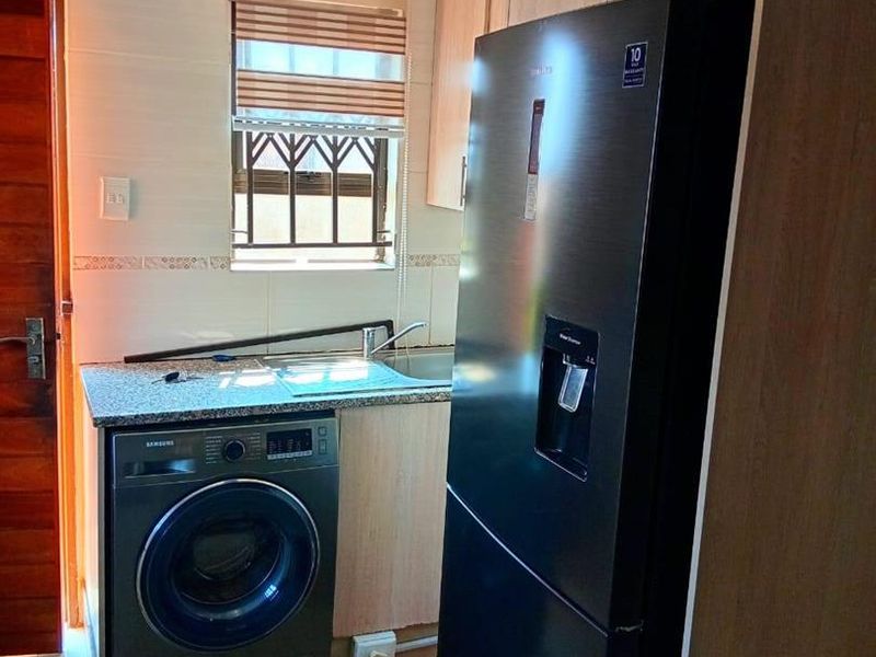 A functional laundry area featuring built-in cabinetry, a granite countertop with an integrated sink, and tiled flooring.