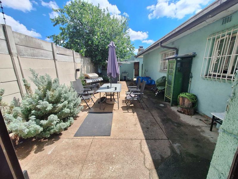 Rear exterior area featuring a concrete patio, precast boundary wall, and security bars on windows, offering potential for outdoor living space improvement.