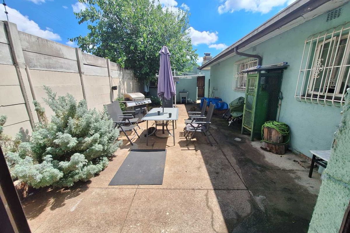 Rear exterior area featuring a concrete patio, precast boundary wall, and security bars on windows, offering potential for outdoor living space improvement.