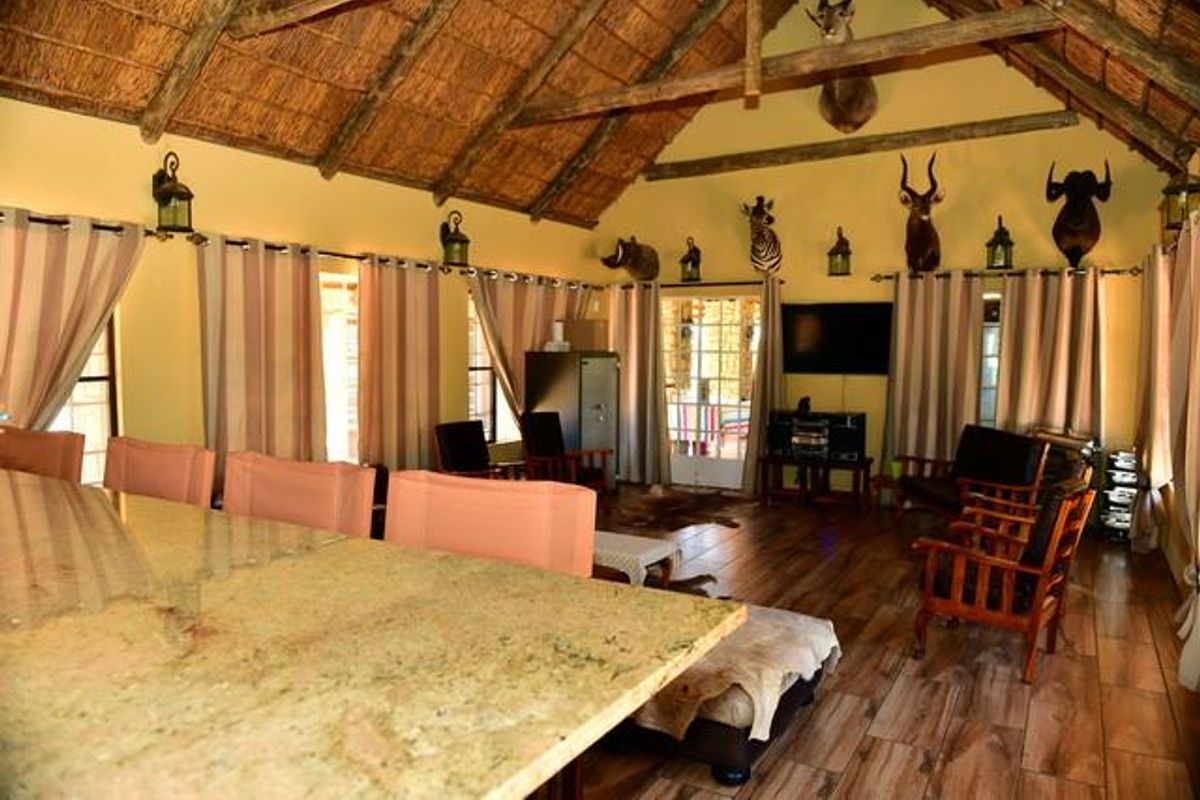 Spacious living area featuring a high vaulted thatched roof with exposed timber trusses, tiled flooring, and a large granite-topped island.