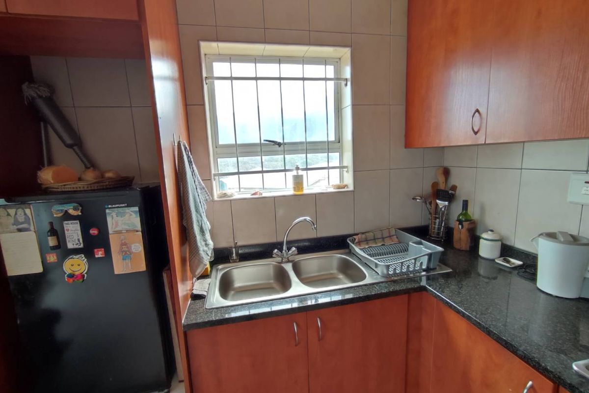 A functional kitchen featuring laminate cabinetry, granite countertops, and a double bowl stainless steel sink with a tiled backsplash.