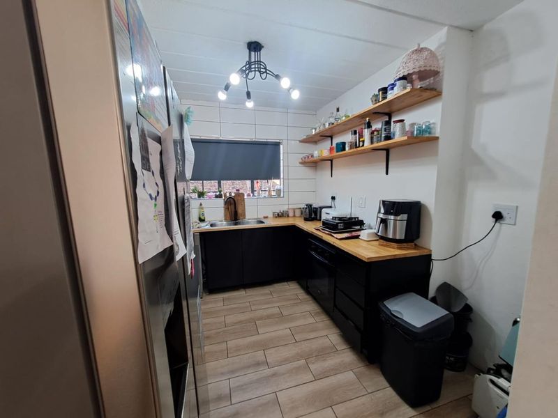 A functional kitchen featuring dark cabinetry, wooden countertops, open shelving, and a tiled backsplash, providing a modern and efficient workspace.