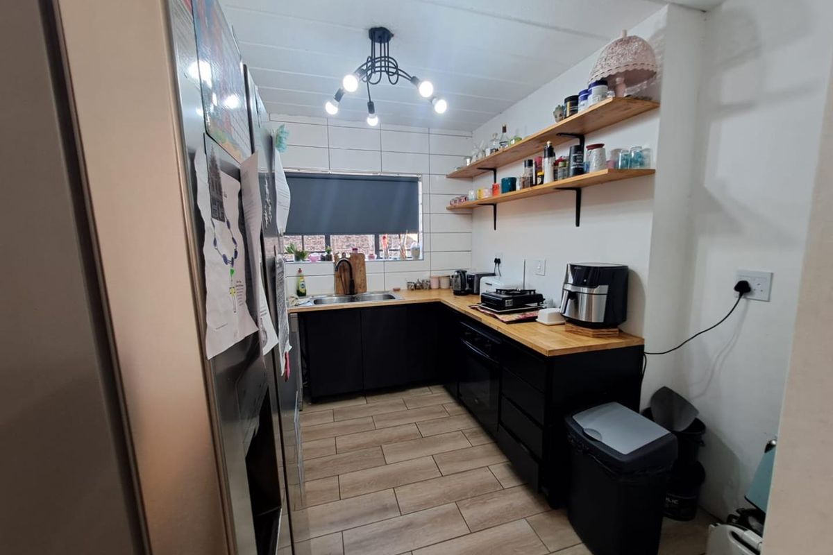 A functional kitchen featuring dark cabinetry, wooden countertops, open shelving, and a tiled backsplash, providing a modern and efficient workspace.