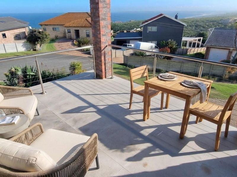 Elevated balcony featuring tiled flooring, a brick support pillar, and a stainless steel balustrade with expansive coastal and neighbourhood views.