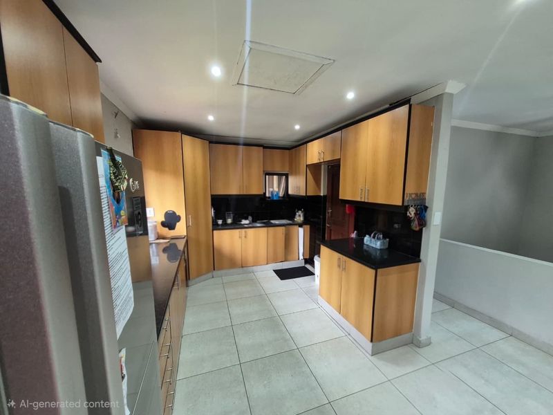 A functional kitchen featuring wood-finish cabinetry, black granite countertops, tiled flooring, and recessed lighting, offering a practical layout for daily meal preparation.
