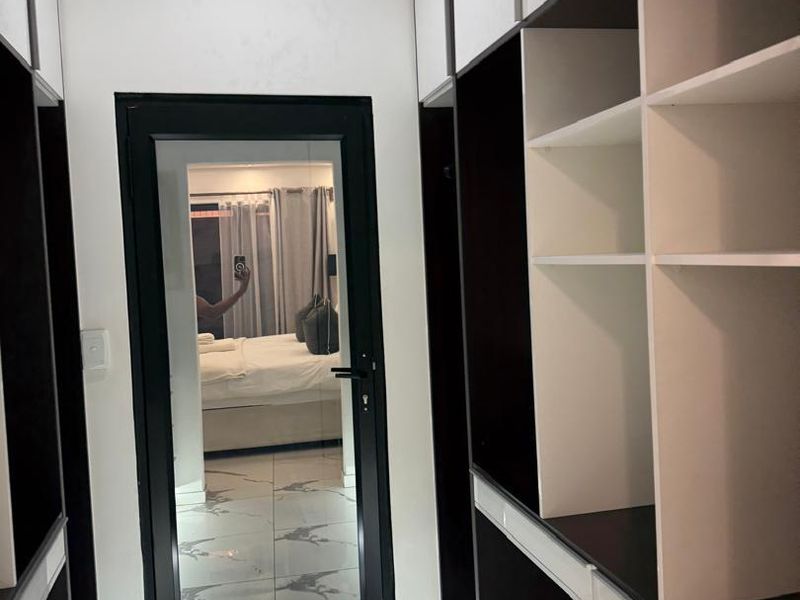 A modern walk-in closet or dressing area featuring sleek built-in cabinetry, high-gloss tiled flooring, and recessed lighting.