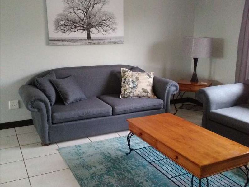 A comfortable living room featuring neutral wall tones and clean tiled flooring, providing a functional and well-maintained space.