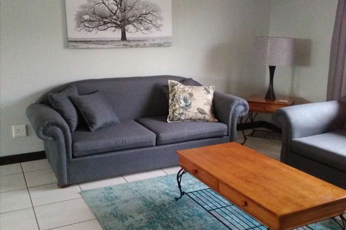 A comfortable living room featuring neutral wall tones and clean tiled flooring, providing a functional and well-maintained space.