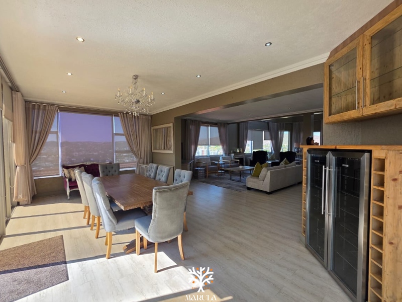Spacious open-plan living and dining area featuring laminate flooring, recessed lighting, and a custom built-in wine storage unit with integrated cooler.