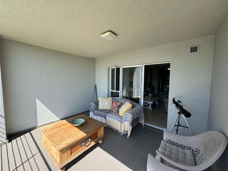 A covered balcony featuring tiled flooring and a sliding glass door providing access to the interior living space.