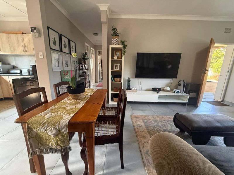 Open-plan living and dining area featuring tiled flooring, neutral walls, and an adjacent kitchen space with built-in cabinetry.