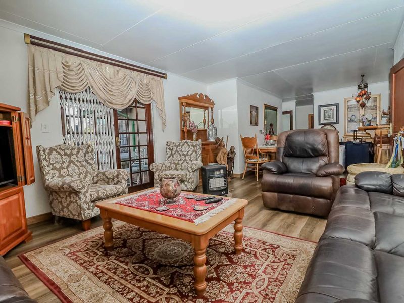A spacious living room featuring laminate flooring and a sliding glass door with a security gate, providing access to the outdoor area.