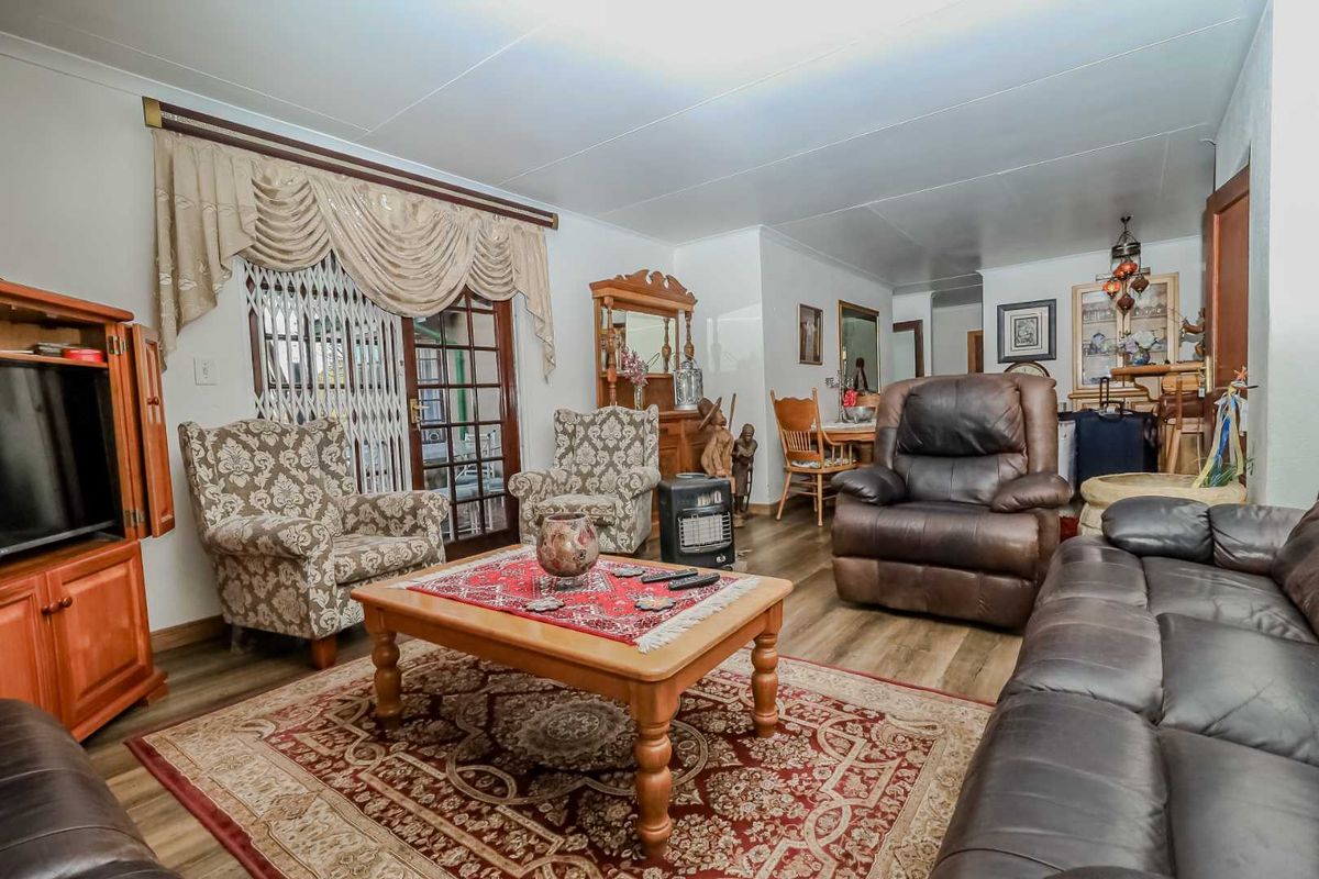 A spacious living room featuring laminate flooring and a sliding glass door with a security gate, providing access to the outdoor area.