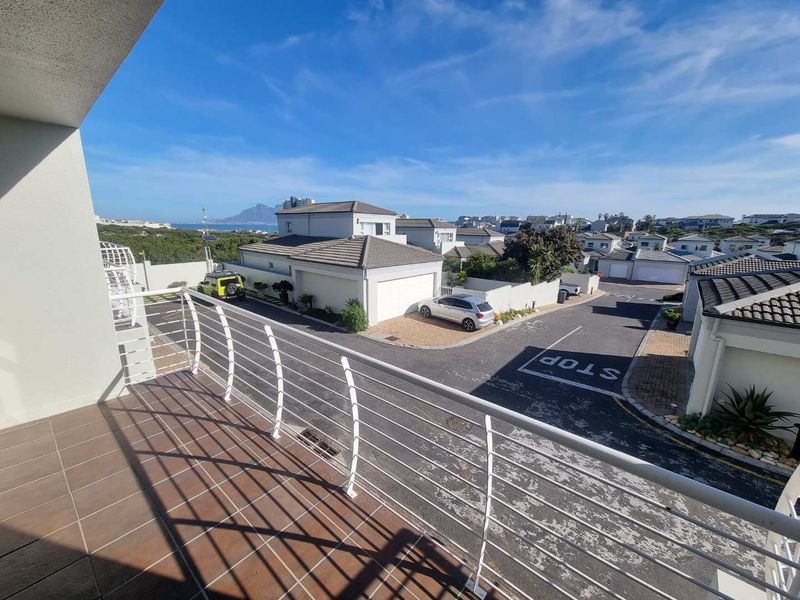 An elevated balcony with tiled flooring and a metal balustrade, offering an expansive view over the residential estate and surrounding neighbourhood.