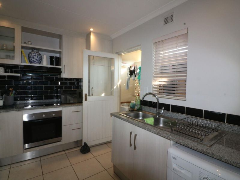 Functional kitchen featuring granite countertops, built-in cabinetry, stainless steel sink, and integrated oven with a tiled backsplash.
